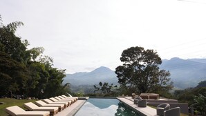 A pool area with lounge chairs and a view of mountains.