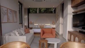 A modern hotel room with a bed, sofa, two wooden chairs, a small table, a TV, and a wall with a nature-themed mural.
