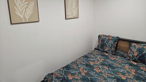A bedroom with a bed, two wall-mounted artworks, and a patterned bedspread. - Cosy apartments Valenciennes center Train station and streetcar on foot (Valenciennes)