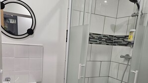 A modern bathroom with a glass-enclosed shower, a white sink, and a mirror with a black frame. - Cosy apartments Valenciennes center Train station and streetcar on foot (Valenciennes)