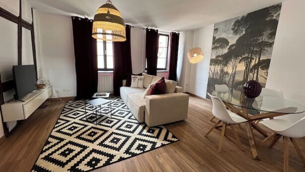 Un salon moderne avec un canapé, une table à manger en verre et un tapis à motifs.