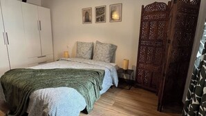 Une chambre à coucher comprenant un lit, une armoire, une table de chevet et une porte décorative en bois.