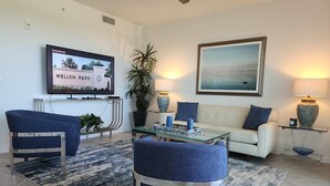 Un salon moderne comprenant un canapé, deux fauteuils, une table basse et un téléviseur affichant les informations sur la communauté et le parc de Wellen.