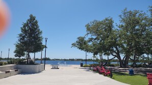 Un parc au bord de l’eau, doté d’une promenade en béton, de bancs et d’arbres.