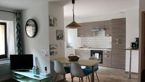 Una cocina moderna con armarios de madera, un comedor con mesa y sillas, y un televisor sobre un mueble.