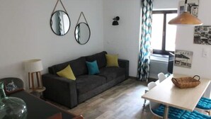 Una sala de estar con sofá, mesa de comedor y lámpara.