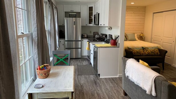 Un espace de vie compact comprenant un coin cuisine, un coin repas et un lit.