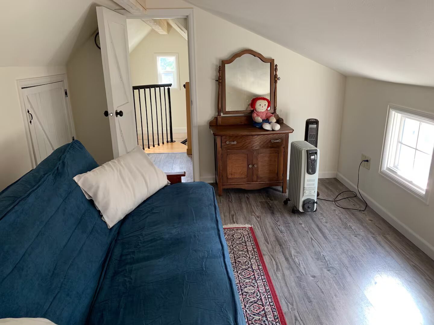 Ein Schlafzimmer mit Bett, Schminktisch, Spiegel, Heizkörper und einem Fenster.