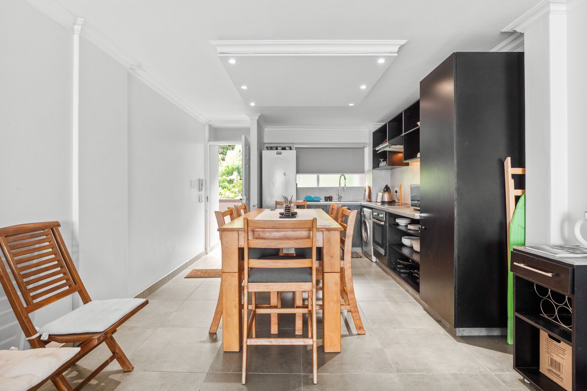 Une cuisine moderne avec un coin repas, comprenant une table et des chaises en bois, un réfrigérateur noir et un four encastré.