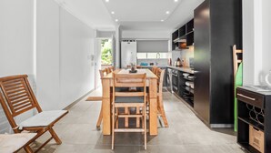Una cocina moderna con comedor, que presenta una mesa y sillas de madera, un refrigerador negro y un horno empotrado.