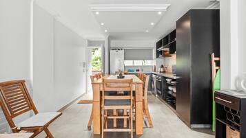 Une cuisine moderne avec un coin repas, comprenant une table et des chaises en bois, un réfrigérateur noir et un four encastré.