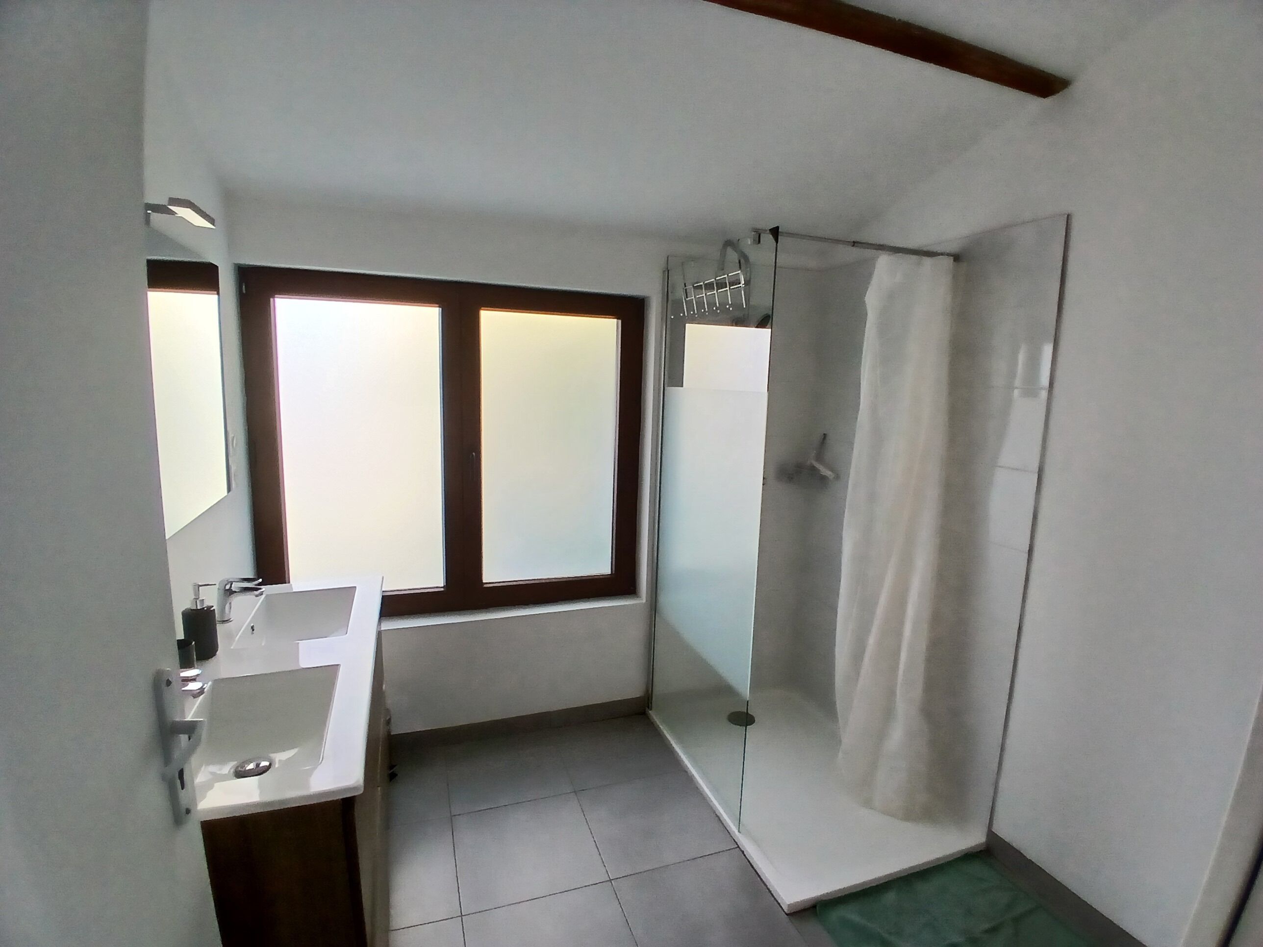 A bathroom with a sink, mirror, and shower.