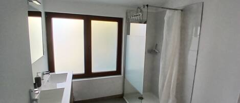 A bathroom with a sink, mirror, and shower.