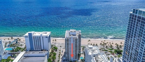 Un paisaje urbano costero con rascacielos, una playa y un mar azul claro.