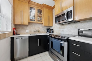 A modern kitchen with wooden cabinets, stainless steel appliances, and a tiled backsplash.