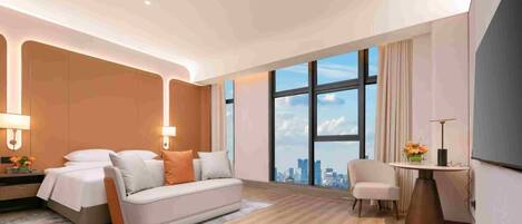 A modern hotel room with a large bed, a sofa, a desk, and a view of the city.
