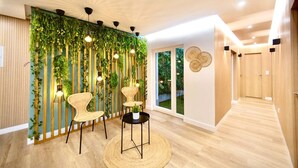 A modern interior with a vertical garden wall, wicker chairs, a round table, and a wooden floor.