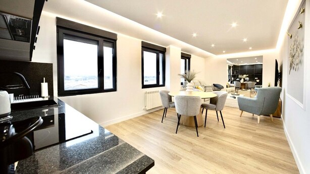A modern kitchen with a granite countertop, a built-in oven, and a window overlooking a cityscape.