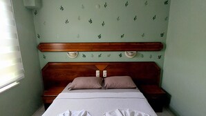 A hotel room with a bed, two bedside tables, a headboard, and a wall with a leaf pattern. - Mar Soleil Apartments (Marmaris)