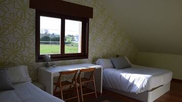 A small, single-room accommodation with two single beds, a desk, and a chair.