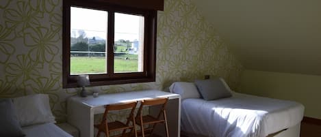 A small, single-room accommodation with two single beds, a desk, and a chair.