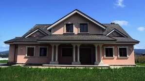 A two-story house with a gabled roof, a front porch with columns, and a symmetrical facade.