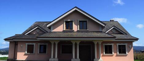 A two-story house with a gabled roof, a front porch with columns, and a symmetrical facade.