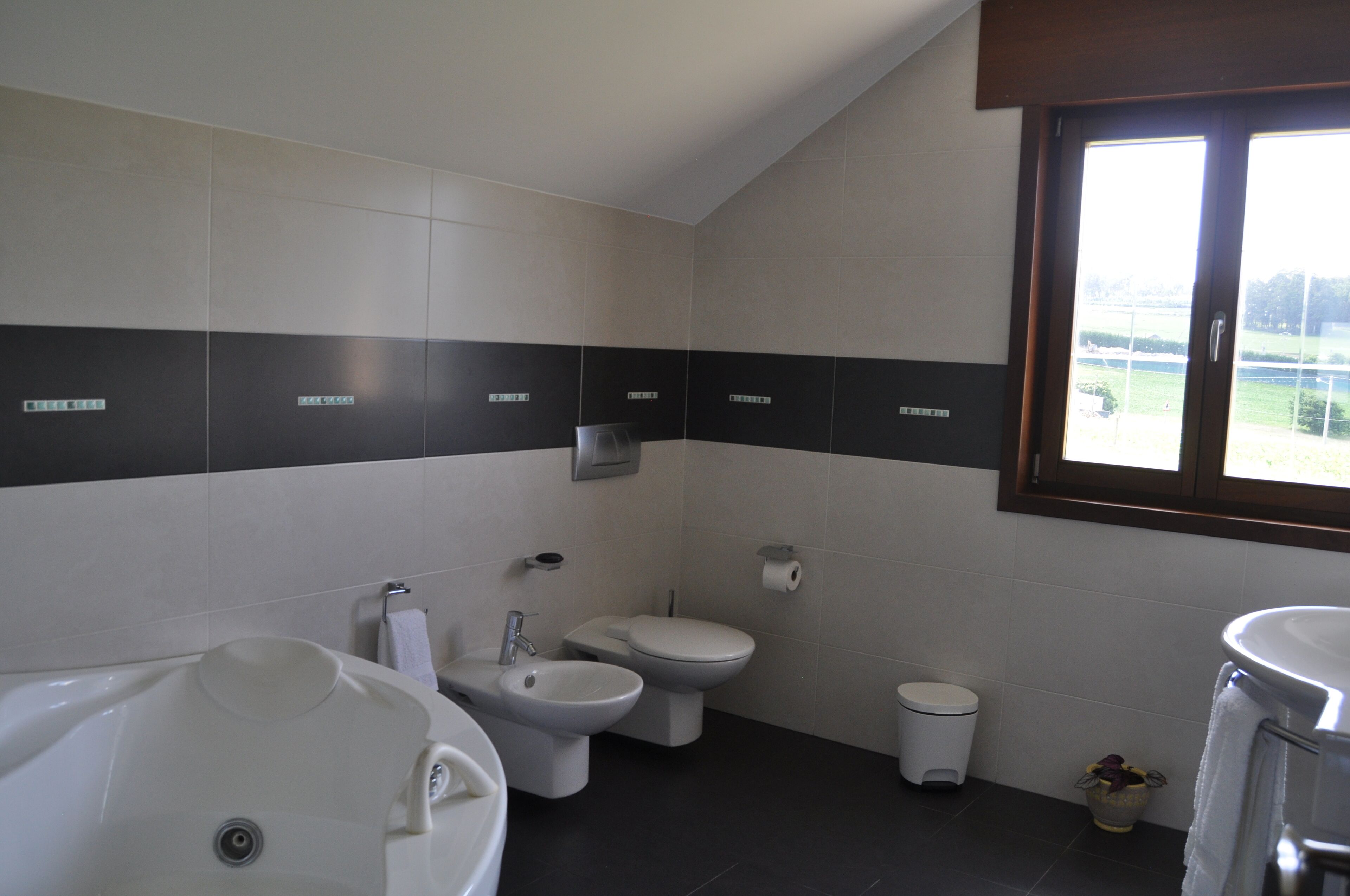 A modern bathroom with a bathtub, a sink, a toilet, and a bidet.