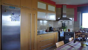 A kitchen with wooden cabinets, a stainless steel refrigerator, a coffee maker, and a window with plants.