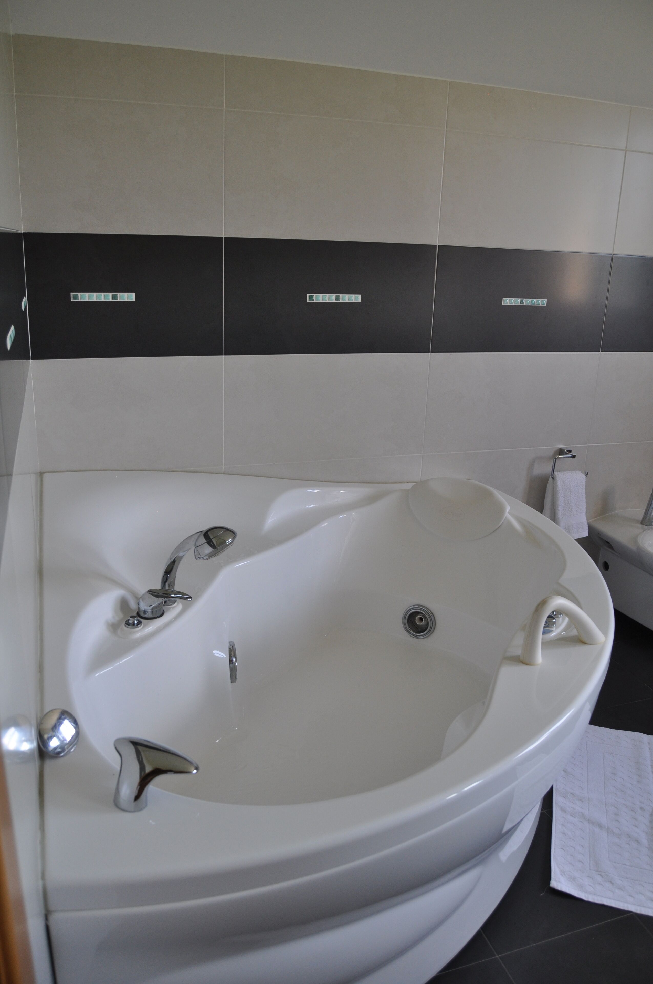A bathroom with a white bathtub, a sink, and a toilet. The walls are tiled in black and white.