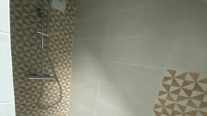 A shower area with a geometric patterned wall, a handheld showerhead, and a wall-mounted faucet. - Studio chic l'Auvétia (Arnage)