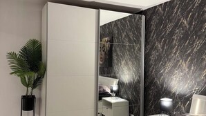 Une chambre à coucher moderne avec un lit, des tables de chevet, un miroir et une plante en pot.