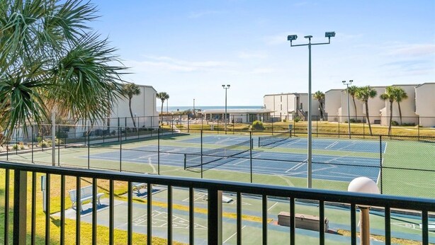 A tennis court with a clear view of the surrounding buildings and a palm tree. - 2BR Condo Sleeps 6 – Pool & Steps to the Beach (Panama City Beach)