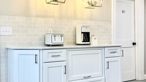 Eine Küche mit weißen Schränken, einem Toaster, einer Kaffeemaschine und zwei Pendelleuchten.