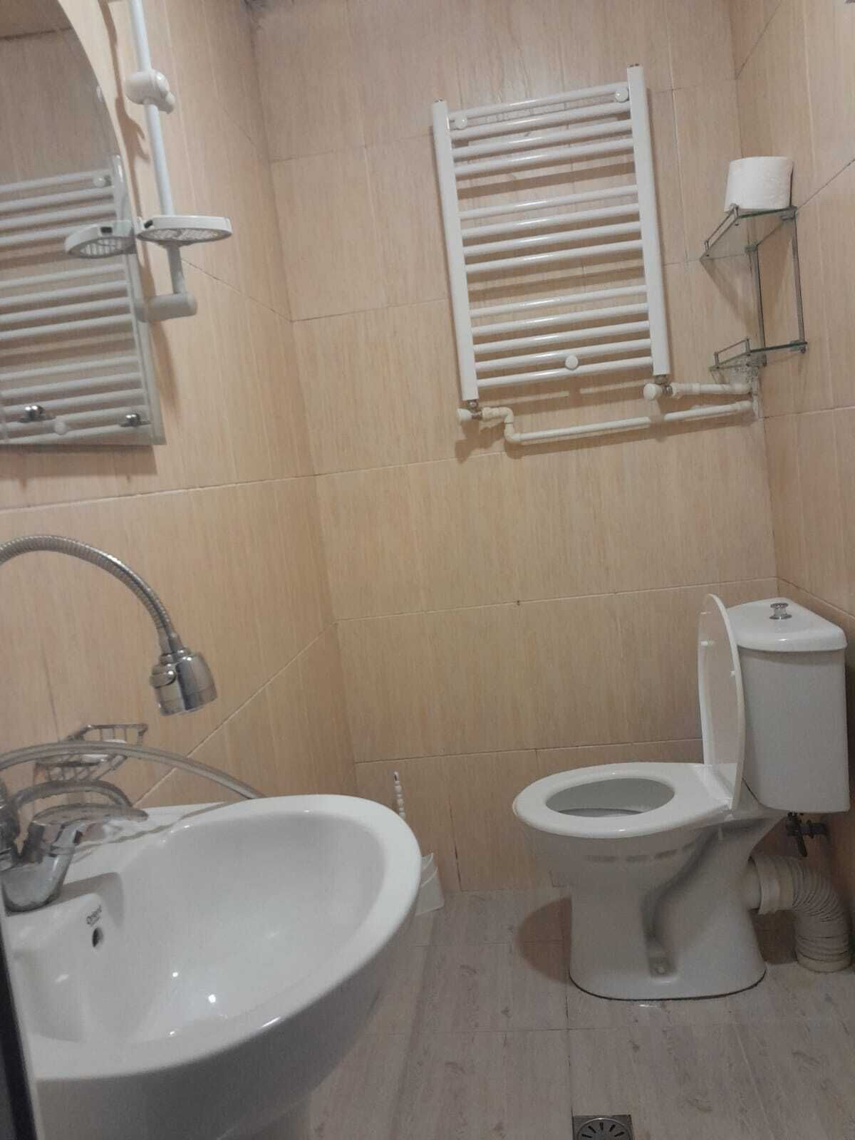 A bathroom with a sink, toilet, and towel rack.