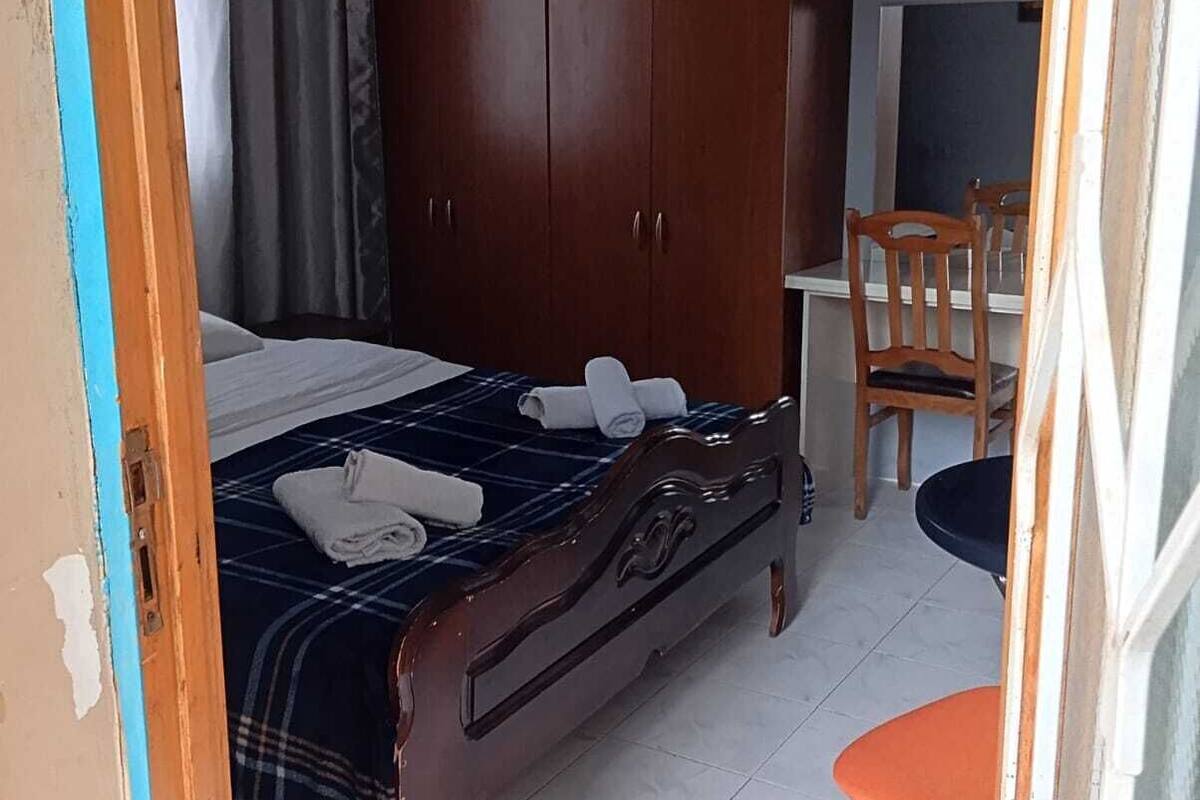 A bedroom with a bed, a wardrobe, a desk, and a chair.