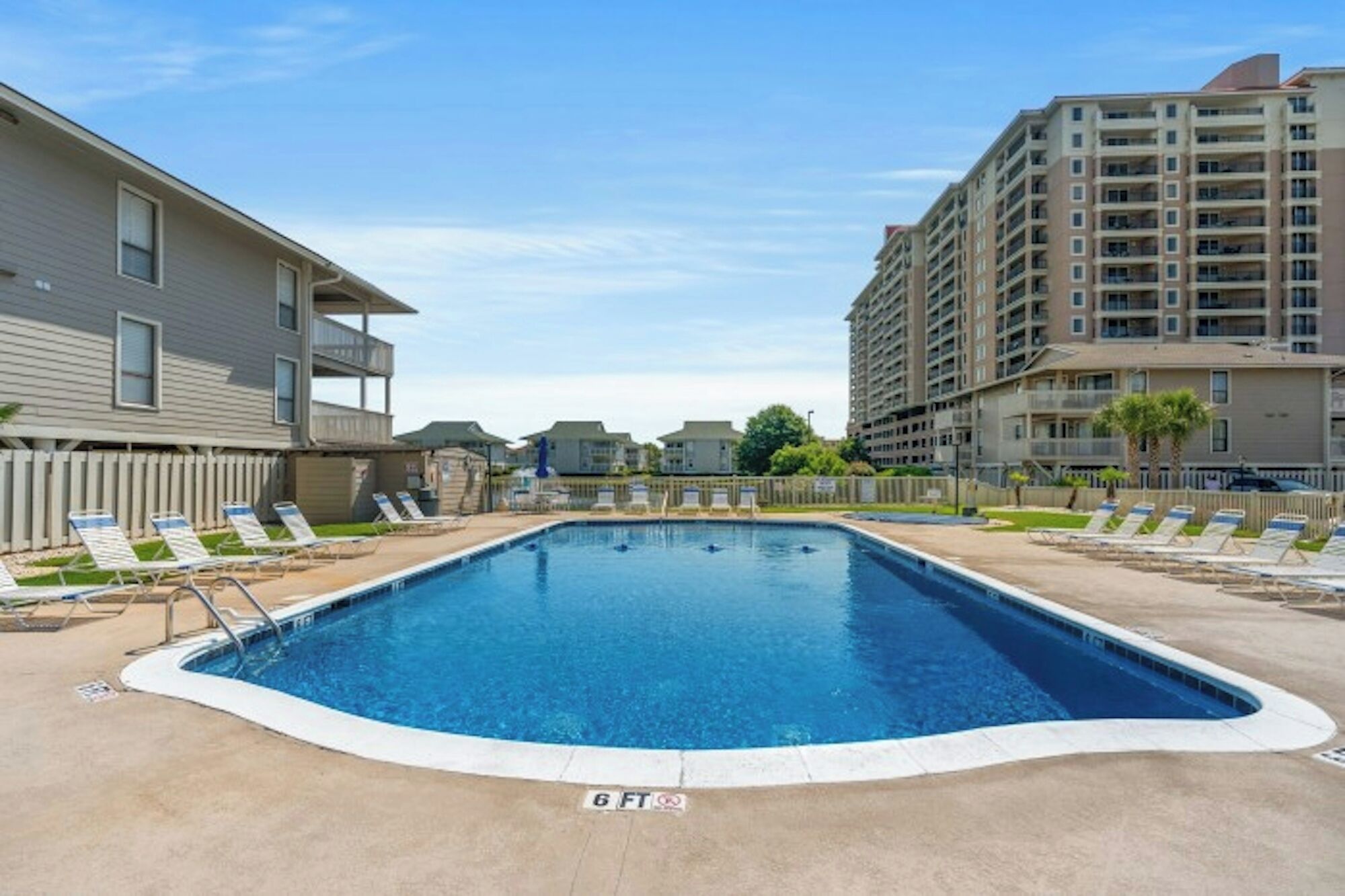 A swimming pool with lounge chairs and a sign indicating a depth of 6 feet.