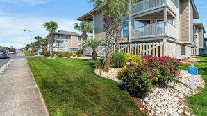 A multi-story residential building with a balcony, surrounded by well-maintained lawns and palm trees. - Tilghman Lakes C4- 2BR/2BA- 2nd Row, Pool (North Myrtle Beach)