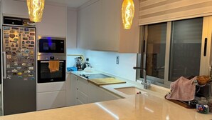 A modern kitchen with a refrigerator, oven, and coffee machine. - Calanegra Apartment with Private Pool - Ground Floor - Puerto de Mazarrón (Mazarrón)