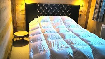 Un dormitorio acogedor con techo de madera, una cama con cabecera estampada con corazones y dos lámparas de noche.