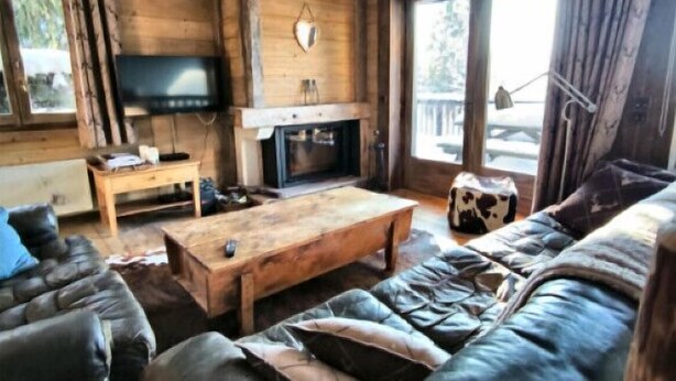 A cozy living room with a wooden interior, a fireplace, a television, and a leather sofa. - Apartment in residence near the Mont d'Arbois (Megève)