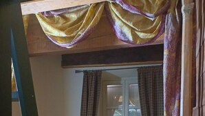 A single bed with a patterned bedspread, a window with curtains, and a wooden ladder. - Apartment with fireplace near the Vauban City (Briançon)
