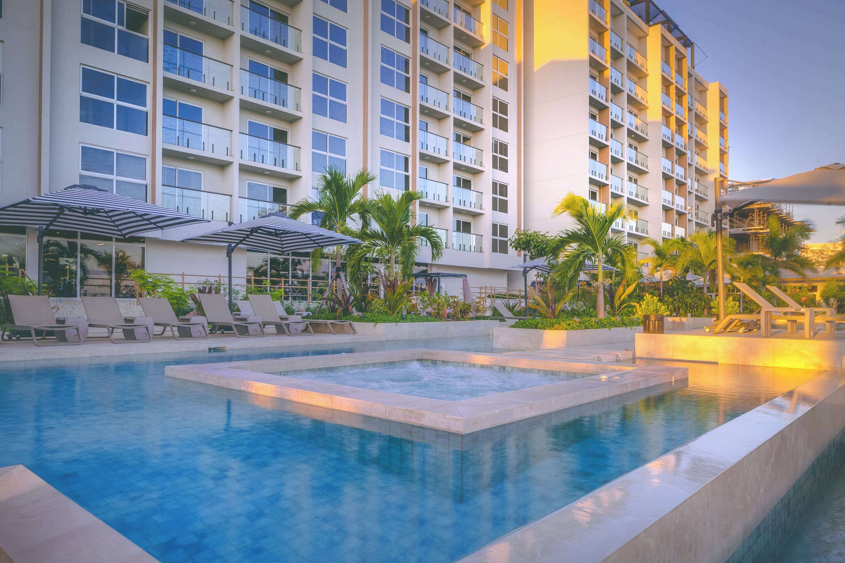Un hôtel doté d’une piscine, de chaises longues et de parasols.