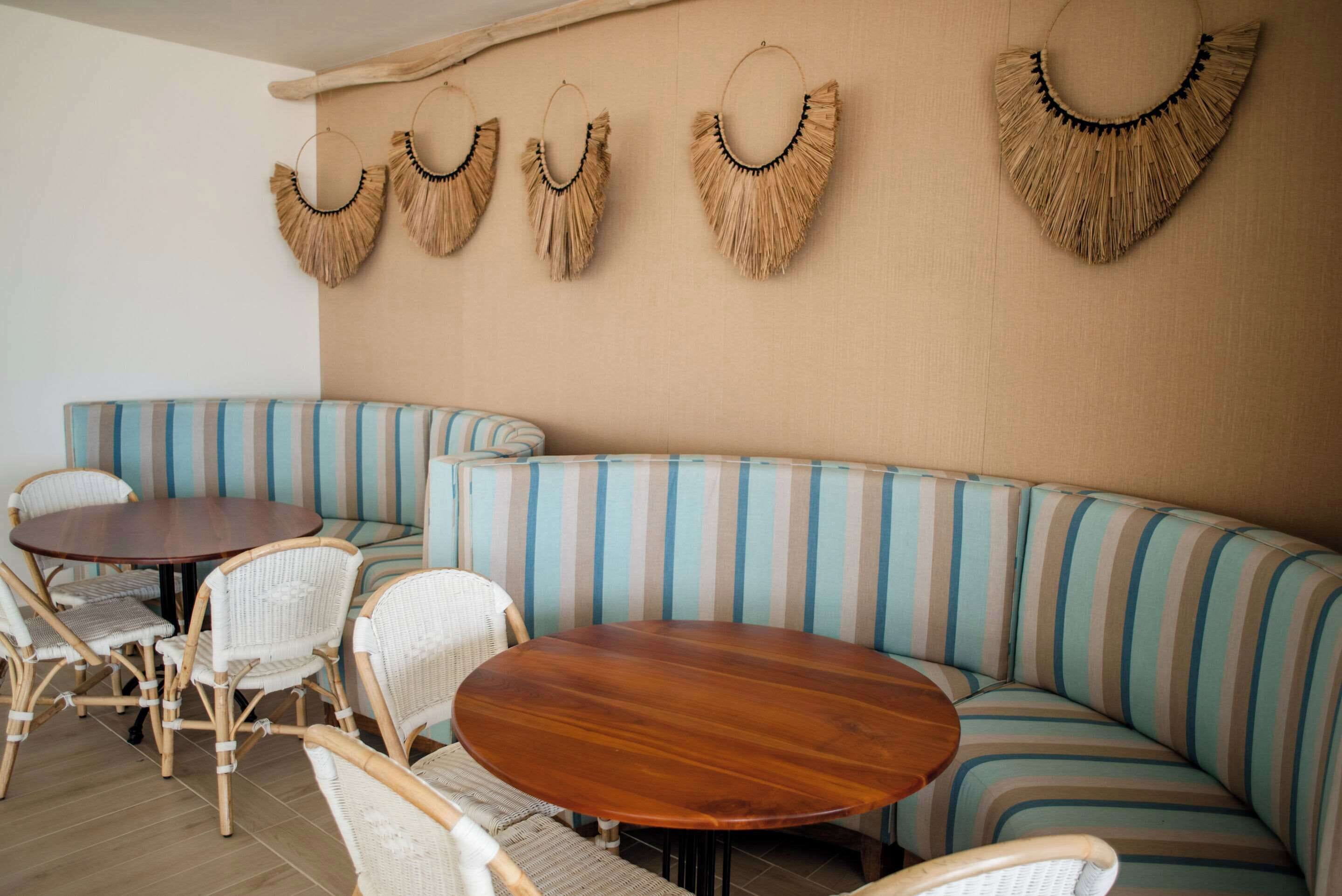 Um quarto com sofá listrado, mesa redonda de madeira e cadeiras de vime.