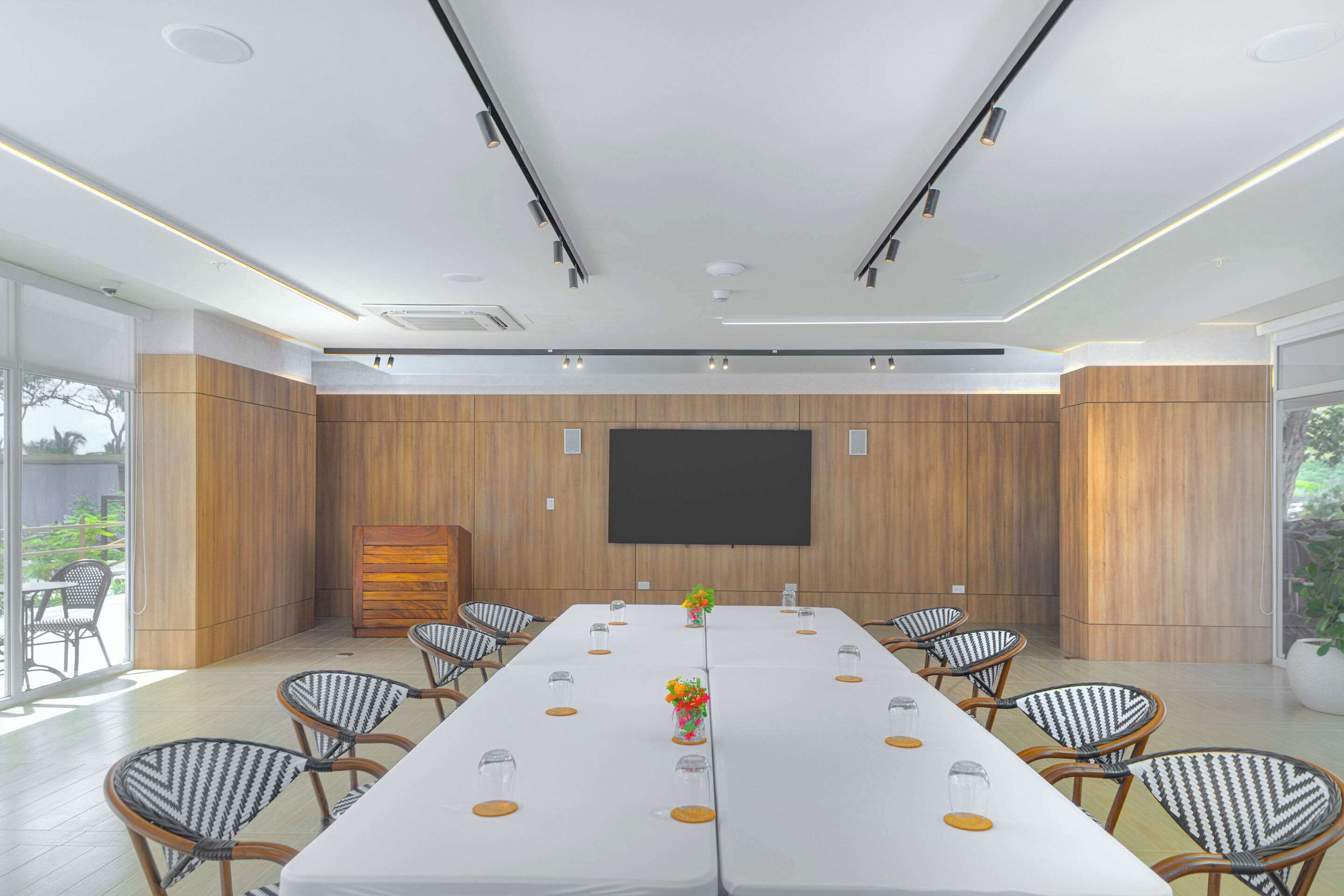 A conference room with a long table, chairs, a flat-screen TV, and a wooden accent wall.