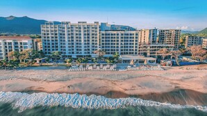 Un hôtel situé en bord de mer, composé de plusieurs immeubles de grande hauteur, avec une plage de sable fin et une eau cristalline.