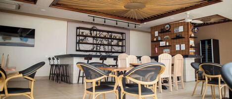 A modern dining area with a central table surrounded by chairs, a ceiling fan, and a decorative light fixture.