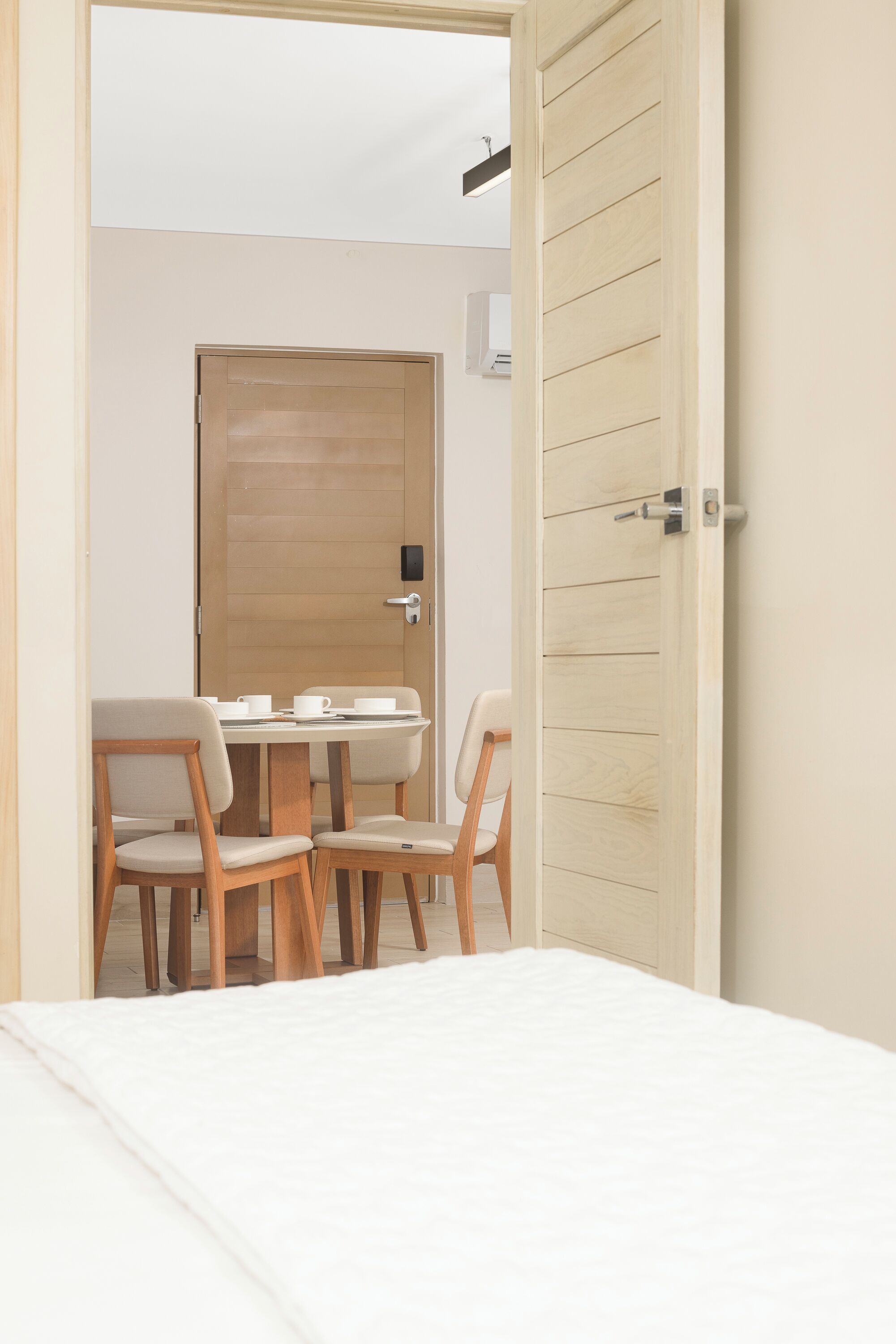 A room with a bed, a wooden door, and a table with chairs.