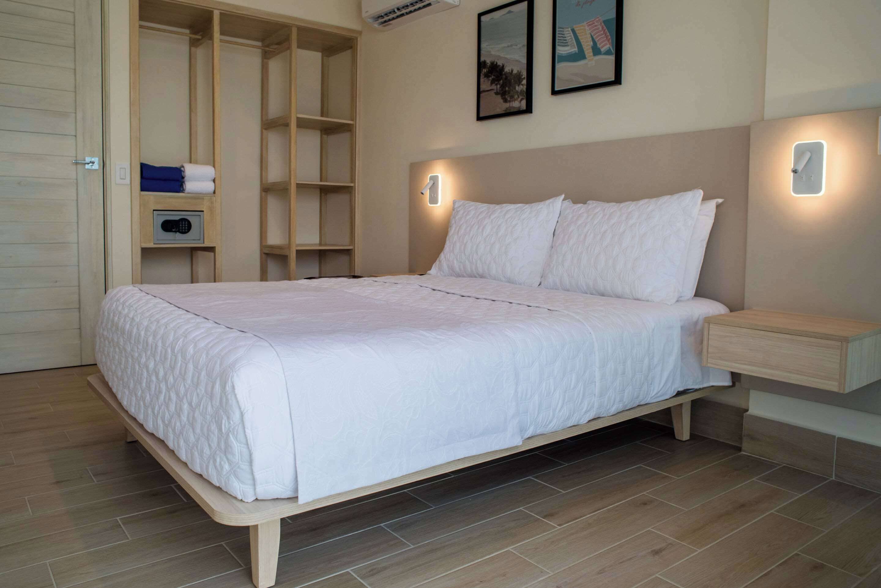A neatly made bed in a room with a built-in wardrobe, a bedside table, and a wall-mounted light fixture.