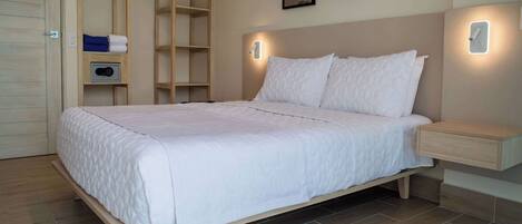 A neatly made bed in a room with a built-in wardrobe, a bedside table, and a wall-mounted light fixture.